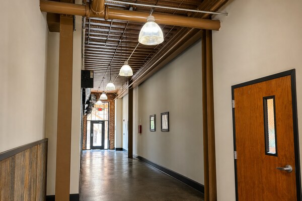 Industrial-style hallway lighting at Porterdale Mill Loft Apartments featuring pendant fixtures, exposed conduit, and high ceilings.